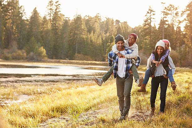 parents giving children piggyback ride on walk by lake